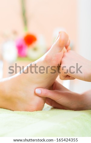 Woman in a nail salon receiving a pedicure by a beautician, she is getting a foot massage