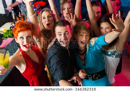 Young people dancing in club or disco, the girls and boys having fun