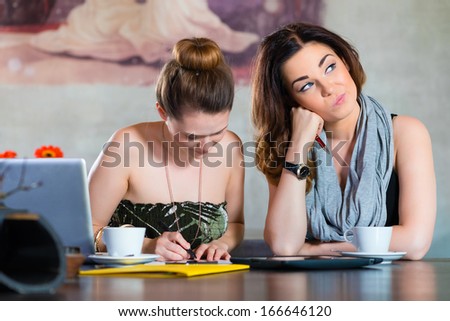 Young women or colleagues working in a cafe or restaurant, on some documents or contract