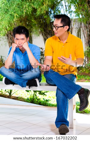 Chinese Asian father talking to his son but will not listening, refusing the good advice