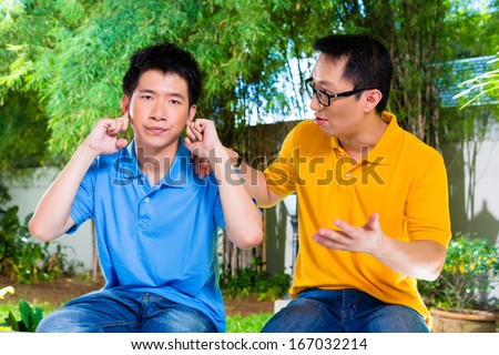 Chinese Asian Father Talking To His Son But He Will Not Listening, Holding His Ears With His Hands Refusing The Good Advice
