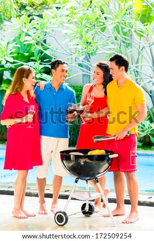 Asian friends having barbecue or BBQ at pool, drinking  wine and celebrating summer time