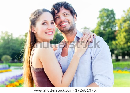 Man and woman or young couple making a trip as tourists in park hugging each other being in love