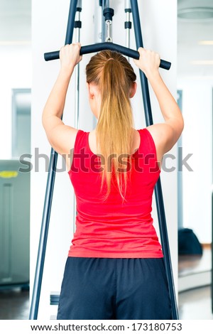 Young woman training on machine in gym or sport center