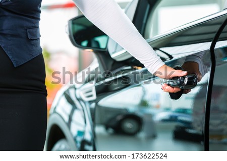 Seller Or Car Salesman And Customer In Dealership, They Shaking Hands, Hands Over The Car Keys And Seal The Purchase Of The Auto Or New Car