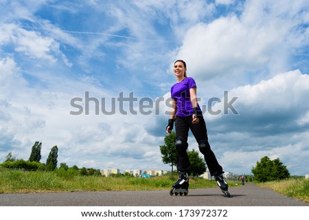 Urban sports - woman skating with Roller blades for better fitness in the city park on a cloudy summer day