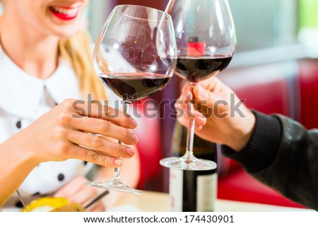Young couple eating fast food and drinking red wine in a American retro fast food diner