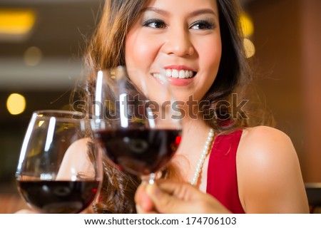 Chinese woman toasting in a restaurant with red wine and a wine glass
