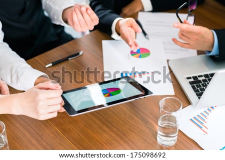 Business - Banker, Manager Or Expert In Meeting Evaluates The Figures On Tablet Computer And Compares The Development Of The Business To Advise And Act As Consultant