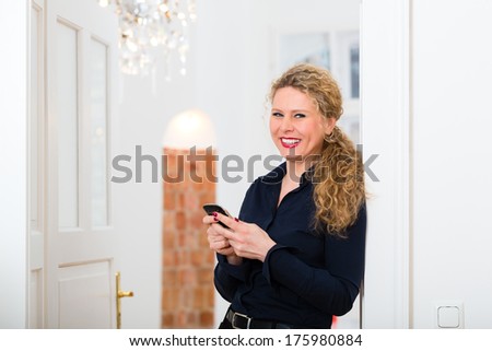Young businesswoman is alone in the evening at home talking to someone on the mobile phone by email or sms