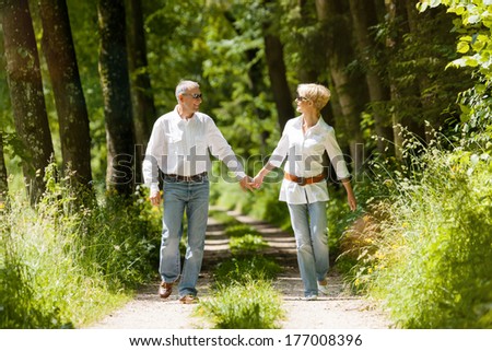 Mature or senior couple running, deeply in love having a walk holding each other tight in late spring or early summer