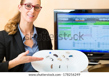 Young Woman or hearing accoustician holding a selection of hearing aids