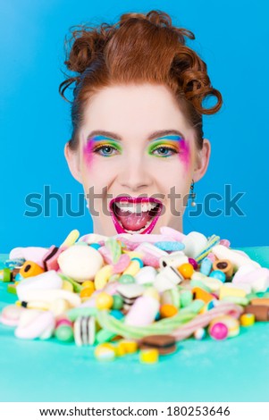 Young woman with many unhealthy sweets or candy in Studio, she have a sweet tooth