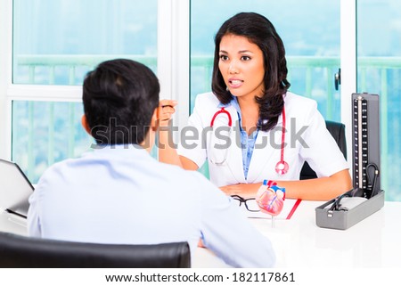 Asian female doctor giving patient medical advice in practice or office
