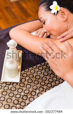 Masseur giving Indonesian Asian woman a aroma therapy massage with essential oil in a beauty wellness spa
