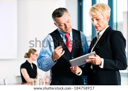 Business - meeting in office, two senior managers are discussing a document on tablet computer
