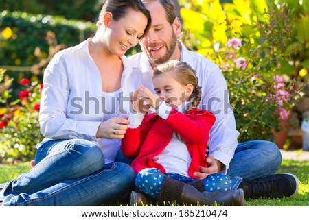 Family with mother, father and daughter together in the garden meadow