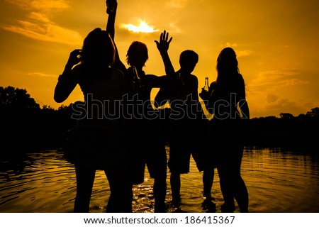 People feeling free in the sunset having a summer party in the water