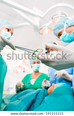 Hospital - surgery team in the operating room or Op of clinic operating on patient in an emergency situation