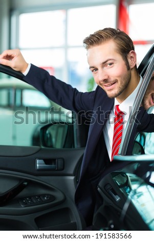 Seller or car salesman in car dealership presenting his new and used cars in the showroom