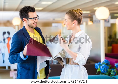 Young couple selecting together seat cover for sofa in furniture store