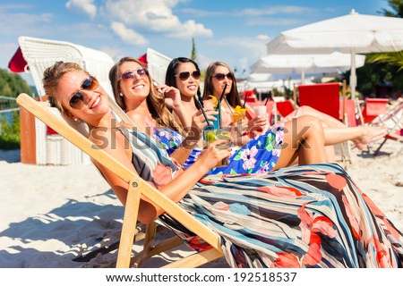 Four woman lying on beach lounger, tanning in the sun