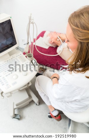 Female doctor testing thyroid of senior patient with surgery ultrasonic device