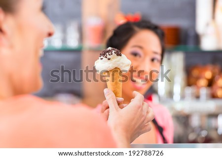 Young female customer and saleswoman in an ice cream parlor with ice cream cornet