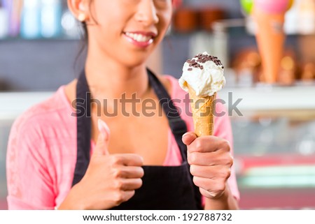Young Asian saleswoman in an ice cream parlor with ice cream cornet