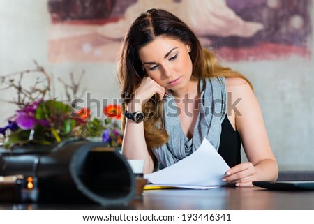 Young woman working or learning in a cafe or restaurant on a contract or some documents