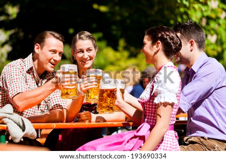 Two happy couple sitting in Bavarian Beer garden and enjoy the beer and the sun