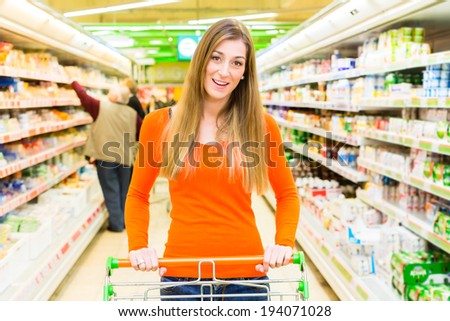 Woman driving shopping cart while grocery shopping in supermarket