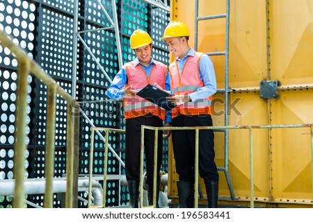 Asian Indonesian construction workers with helmet and safety vest on a building or industrial site in Asia