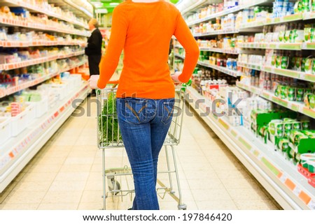 Woman driving shopping cart while grocery shopping in supermarket