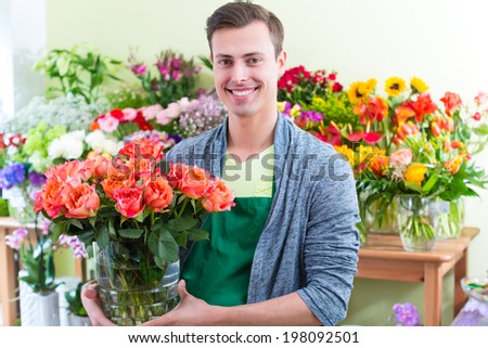 Young handsome florist selling flowers and bouquets in shop