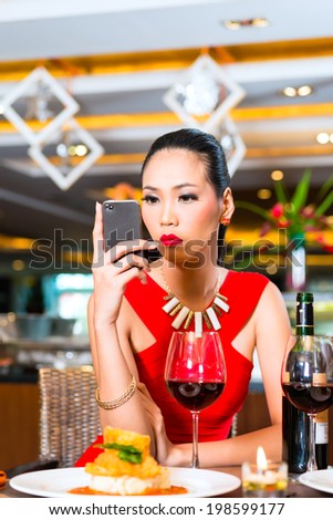 Young woman sitting in restaurant with mobile phone