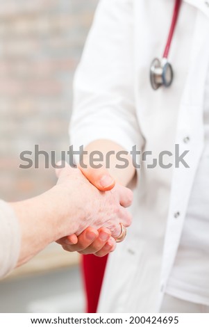 Doctor giving pensioner in surgery comfort and consoling with holding hands
