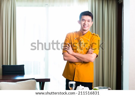 Asian Chinese room service waiter or steward serving guests food in a grand or luxury hotel room