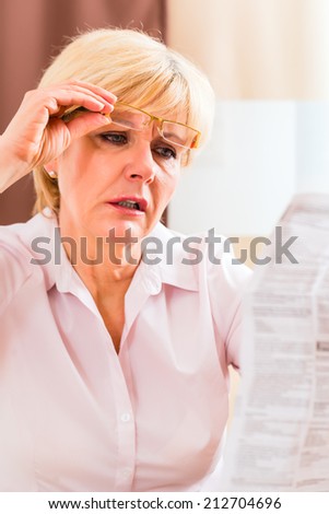 Old woman reading  medicament package insert at home with glasses