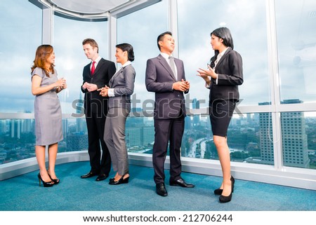 Businesspeople standing and talking in front of office window