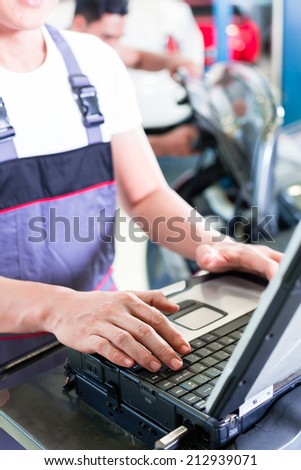 car mechanic checking auto engine with diagnostics tool in his workshop