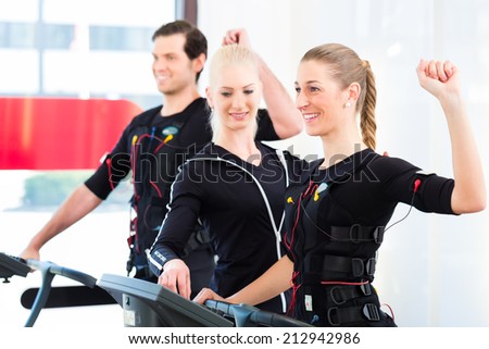 Female coach giving man and woman ems electro muscular stimulation exercise