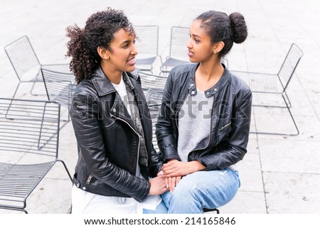 Two north African teen friends sitting together whispering