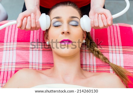 Woman having relaxing herbal bag face massage in wellness spa
