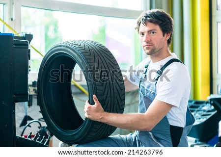 Auto mechanic changing tire in car workshop