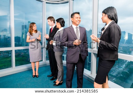 Asian Businesspeople standing and talking in front of office window