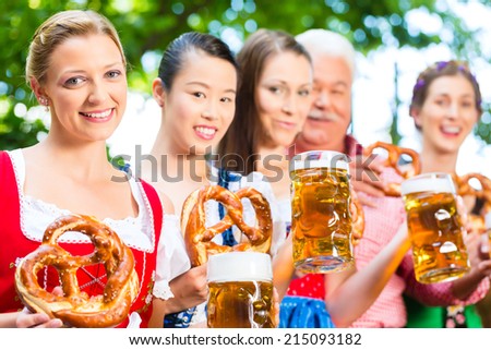 In Beer garden - friends, man and women in Tracht, Dirndl and Lederhosen drinking a fresh beer in Bavaria, Germany