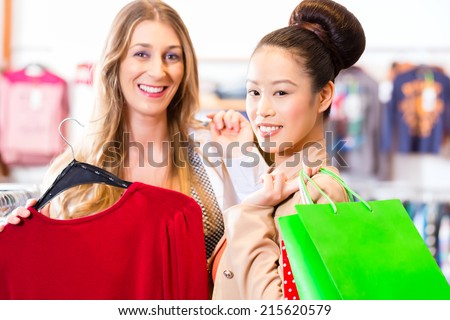 Women shopping in boutique or fashion store buying fashion, Asian and Caucasian friend