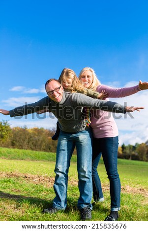 Family playing on meadow in fall or autumn