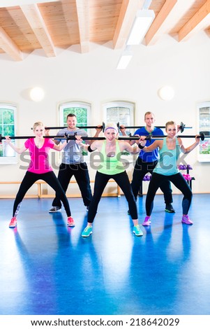 group of young sport people training with barbell at a gym for better fitness